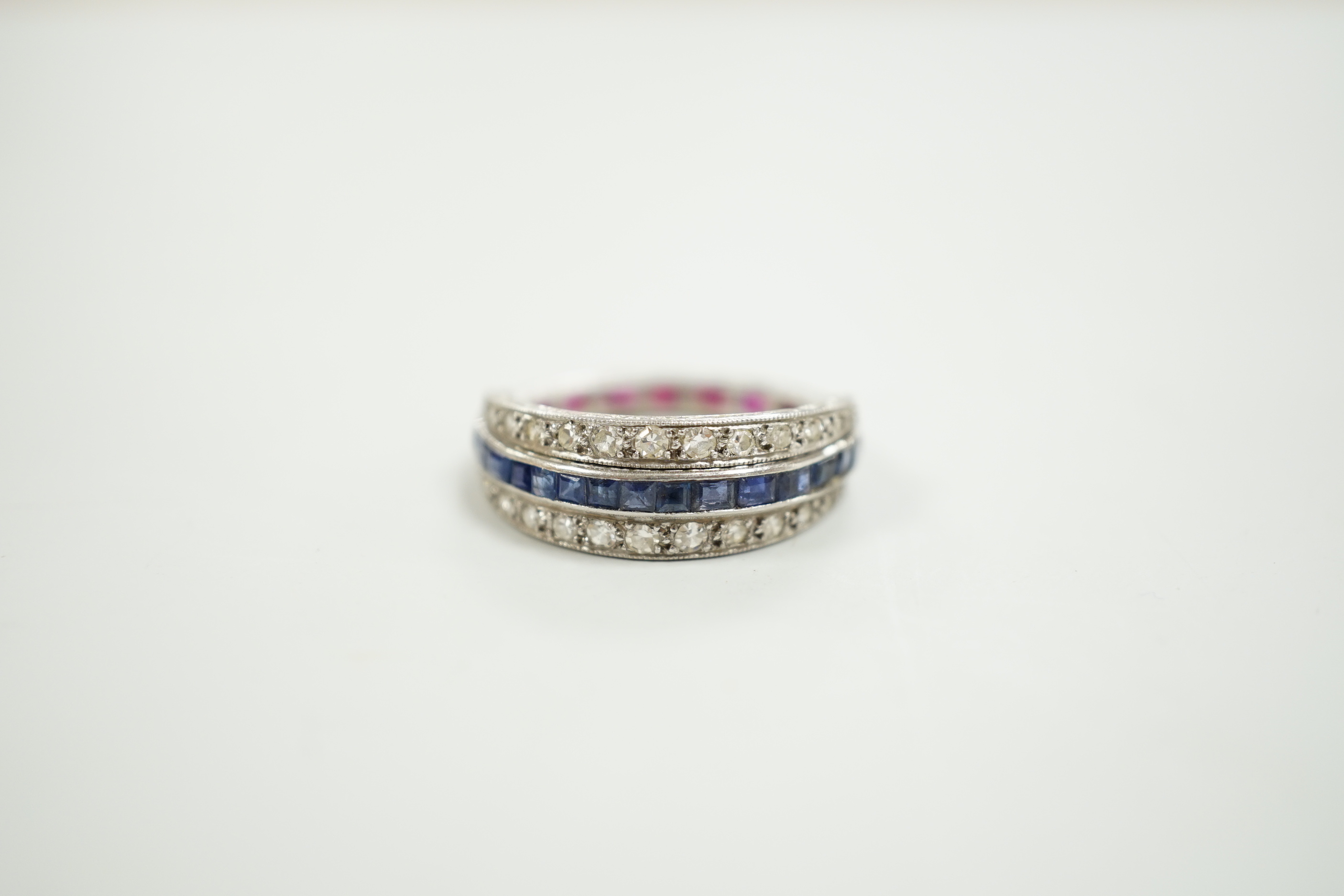 An early to mid 20th century platinum?, ruby, sapphire and diamond set swivelling triple band half eternity ring, size Q, gross weight 4.6 grams.